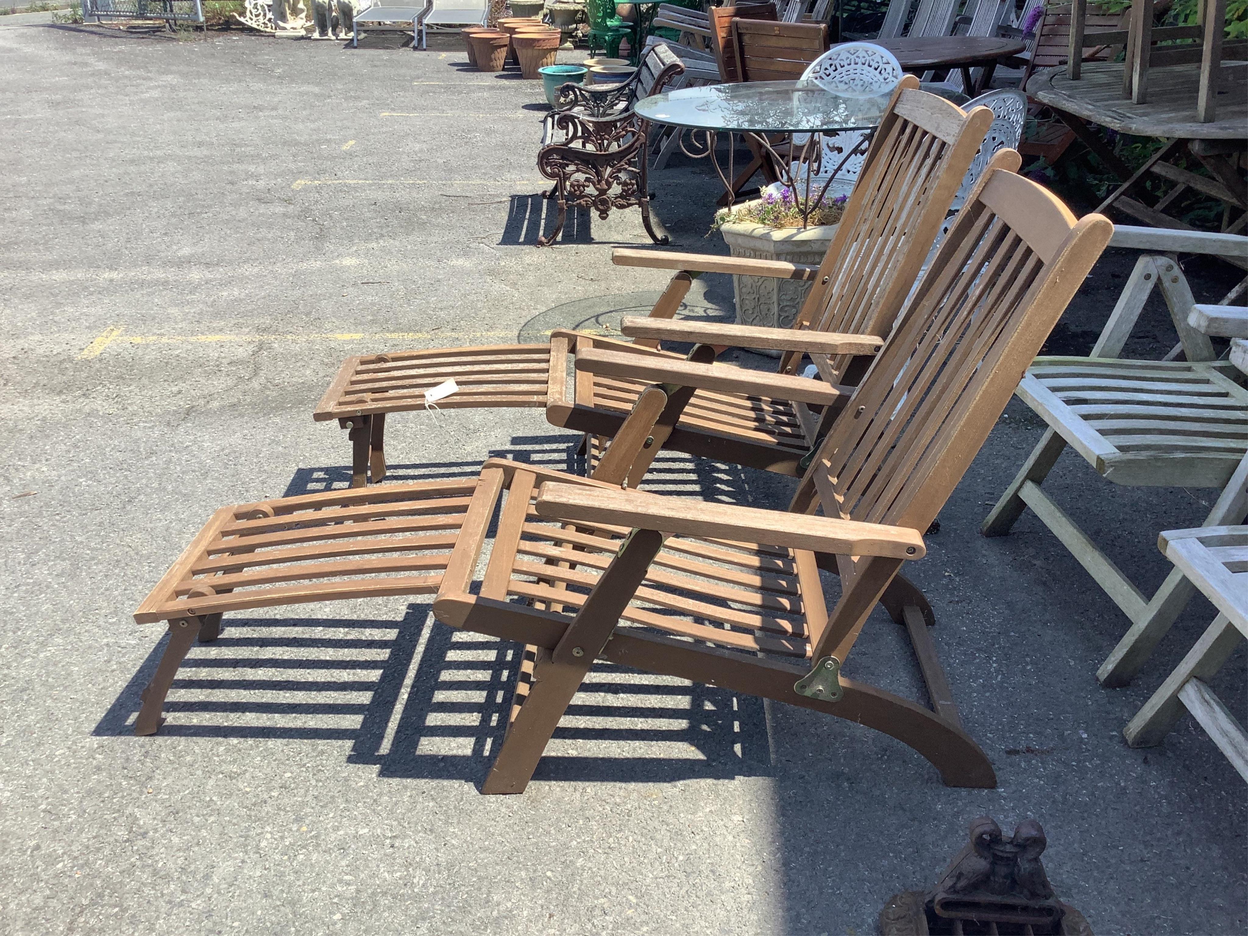 A pair of stained teak garden steamer chairs, width 59cm, height 97cm. Condition - fair